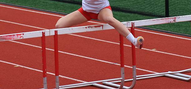istock Female runner over a hurdle during a hurdle track race 2212897101