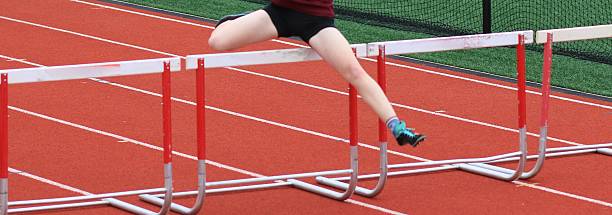 istock Female Track Runner Running Over Hurdles in a Race 2212897105