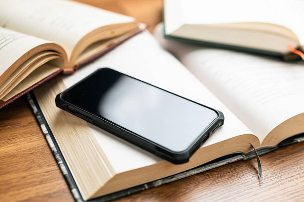 Hardcover cloth hardcover book stacked on white background with white,blank screen smart phone.Conceptual image of education