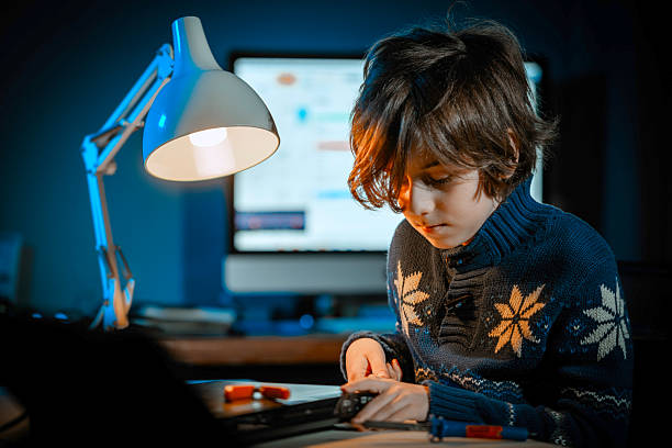 istock Boy repairing electronics components on desk at night 2212913810