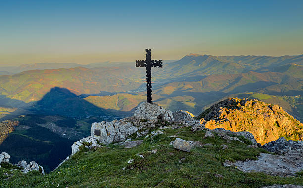 istock Cross standing on mountain peak overlooking scenic valley at sunset. 2212914664