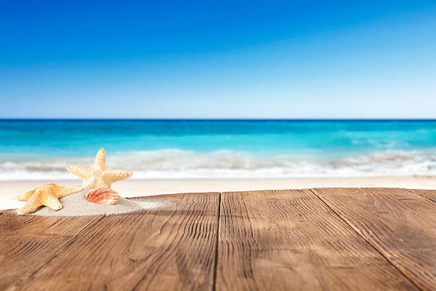 istock Wooden table with copy space with beach and sea and sky background. 2212918015
