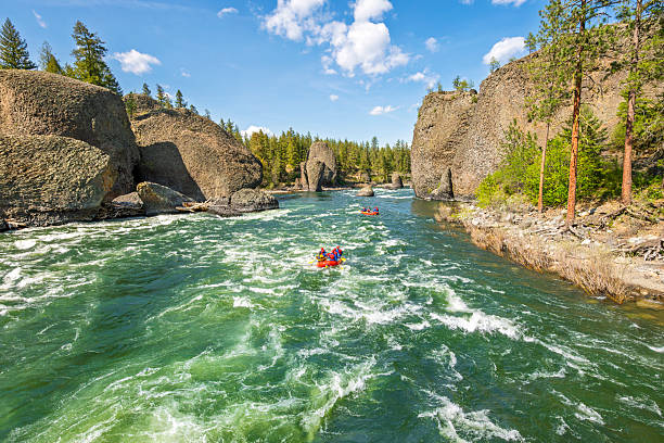 Two groups raft down the rapids along the Spokane River at the Bowl and Pitcher area inside Riverside State Park in Spokane, Washington State USA at spring.