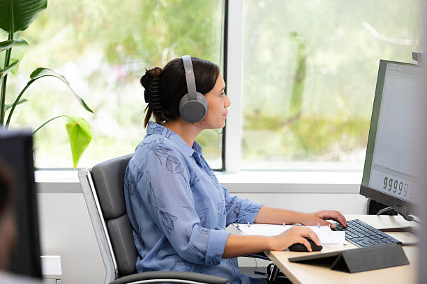 istock Woman using computer with headphones in office 2212920063