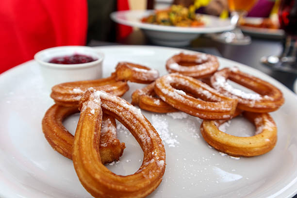 A heap of freshly fried churros is placed on a cooling tray, ready to be sold