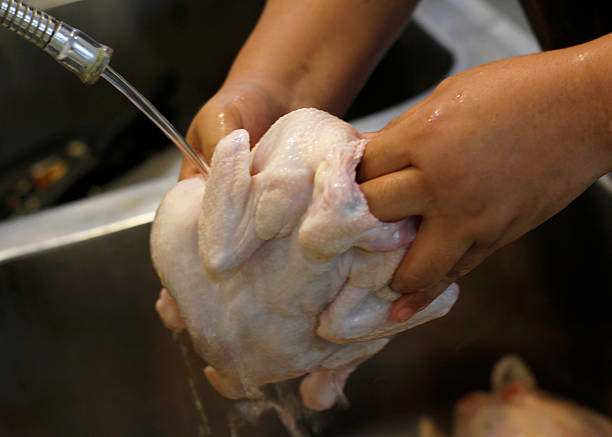 istock Unrecognizable Hand Washing Raw Chicken in Kitchen Sink 2212921866