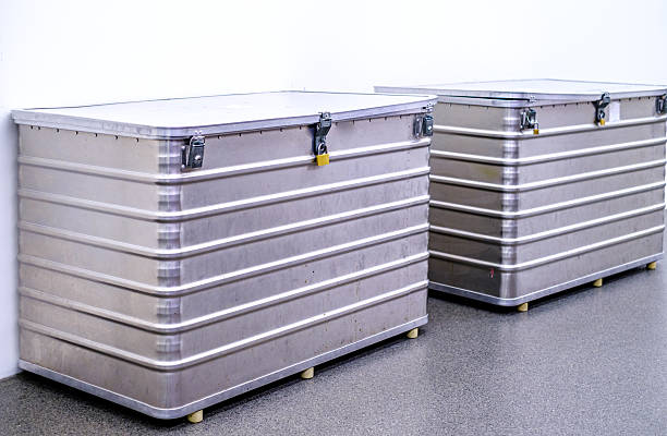 Two large metallic storage containers are positioned side by side against a plain wall, emphasizing sleek lines and functional design in a modern space.