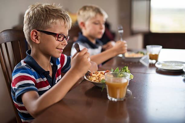 istock Two little boys enjoying a meal at a dining table 2212929380