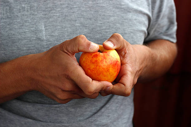 istock peach in hand, man holding peach in hand 2212930272