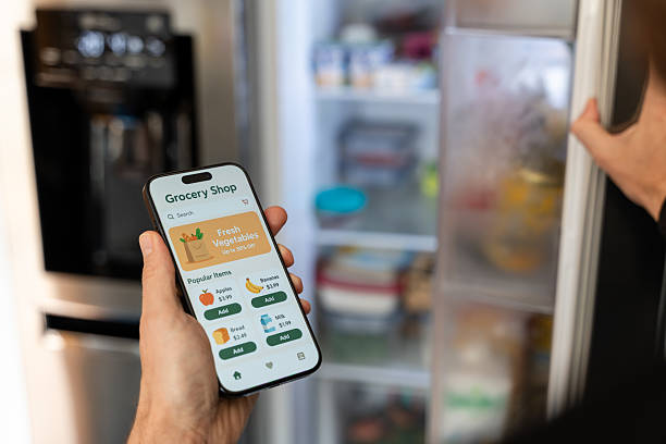 istock Man using grocery shopping app on smartphone and opening refrigerator 2212937800