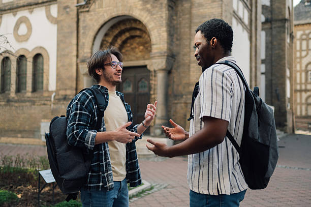 istock Two male students talking and gesturing in front of university building 2212940208