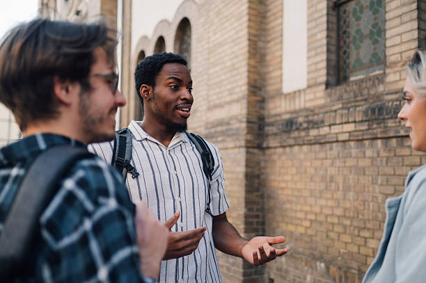 istock Students talking and gesturing in front of university building 2212940211