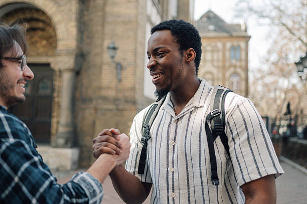 istock Two young men shaking hands in european city 2212940218