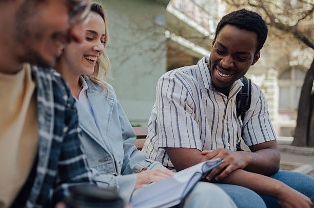 istock Students sharing a book and smiling together on campus 2212940264