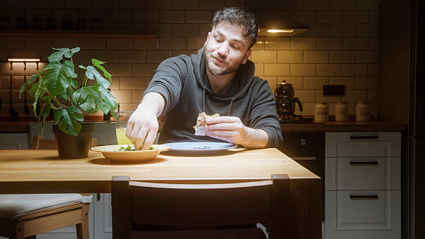 istock Man Enjoying Traditional Middle Eastern Flatbread (Lahmacun) in Cozy Home Kitchen Setting 2212943205