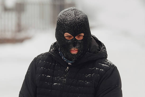 A man wearing a balaclava, trying to stay warm in a snowstorm.