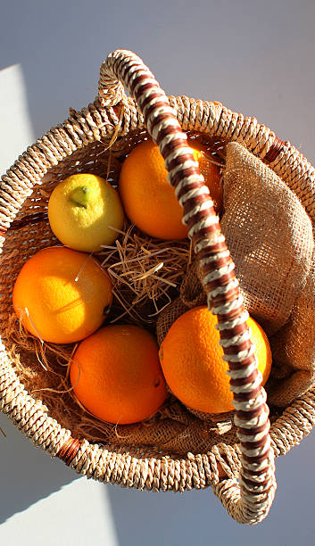 istock Wicker handle basket with citrus fruits on white table in morning time 2212949049