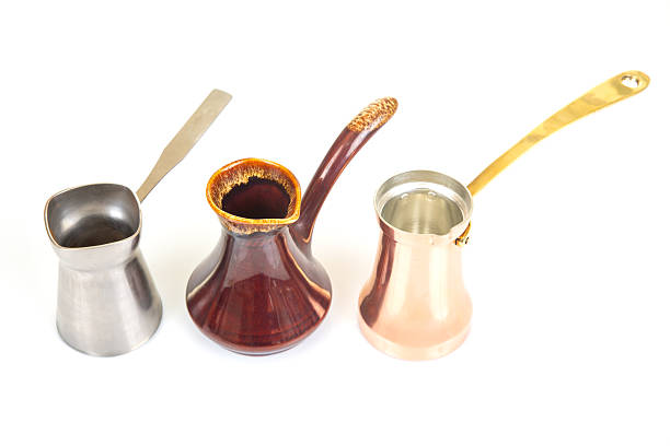 istock Collection of Turkish coffee makers in metallic silver, glossy red ceramic, and shiny copper with gold handles, displayed on a white surface, great for coffee lover and cultural heritage visuals 2212951387