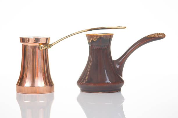 istock Two traditional coffee pots, one copper with a brass handle and another ceramic with a dark brown glaze and wooden handle, isolated on a white background. 2212952225
