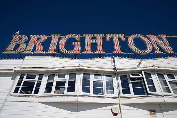 Lone seagull sitting on top of part of a sign displaying the word 'Brighton' near Brighton Beach, England.