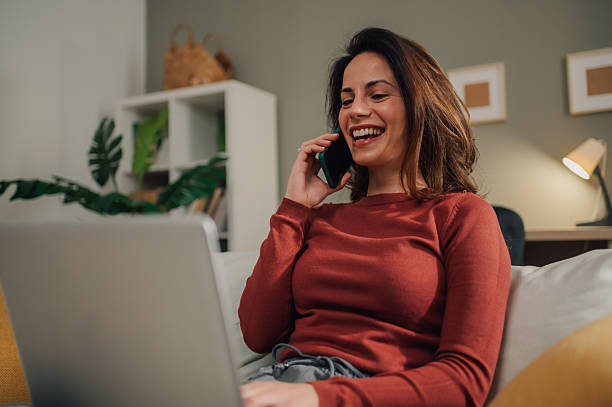 istock Young woman working from home, talking on phone and using laptop 2212958630