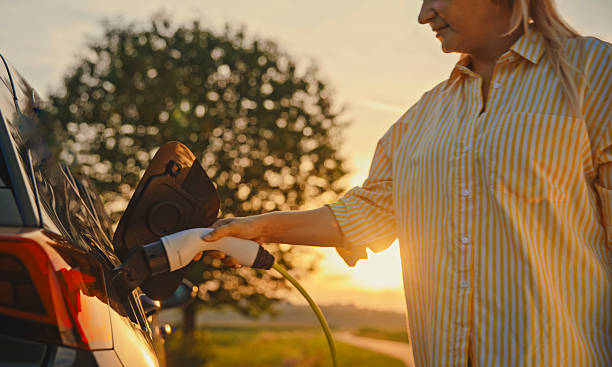 istock Charging Ahead,Woman Powers Electric Car Amidst Countryside Sunset 2212966056