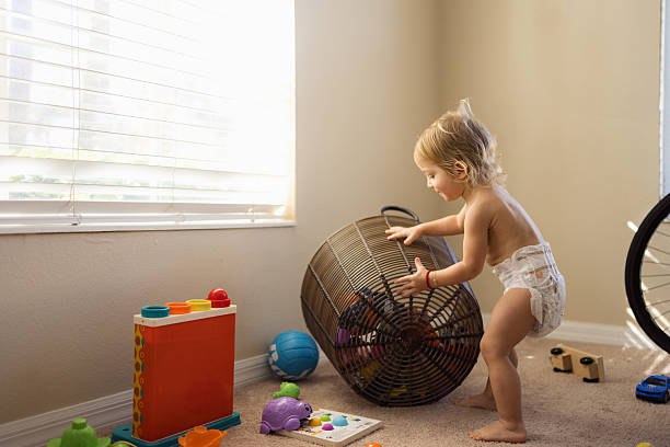 Beautiful toddler boy playing with basketball ball and plastic basket at kindergarten