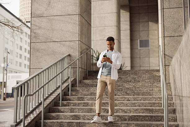 istock Young Man Checking Smartphone While Standing on Outdoor Stone Stairs 2212966185