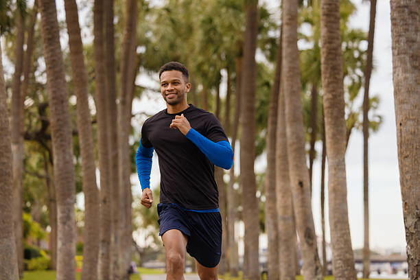 istock Man Jogging Outdoors in Park Surrounded by Palm Trees and Fresh Air 2212966222