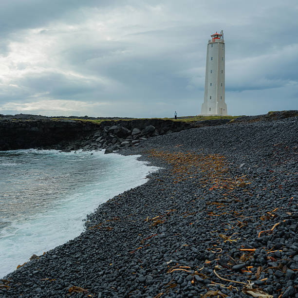 Epic view of white lighthouse surrounded by volcanic landscape in Iceland