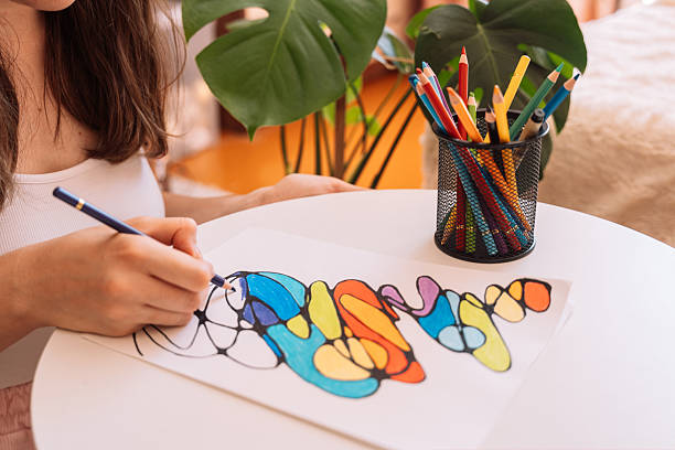 istock Lady paints over a drawing on a white sheet with colored pencils 2212973973