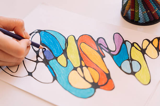 istock Lady paints over a drawing on a white sheet with colored pencils 2212973975
