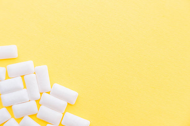 White gum pads scattered on a yellow background.