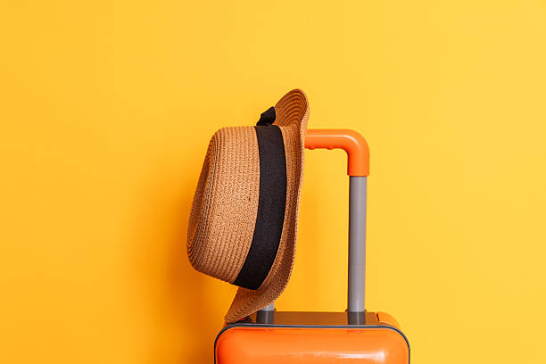 istock Hat on an orange suitcase against a yellow background 2212974170