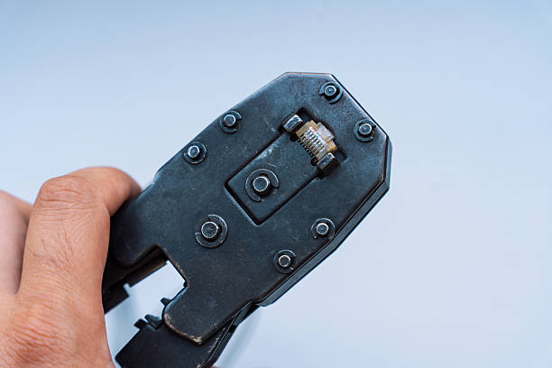 istock Specialist crimps connector on network cable using crimper against gray background 2212974213