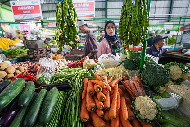 Malang, Indonesia - July 27, 2024 :  A friendly vendor in Malang, Indonesia, is busy preparing and serving a selection of local dishes at her vibrant market stall, providing a glimpse into the heart of Indonesian street food culture.