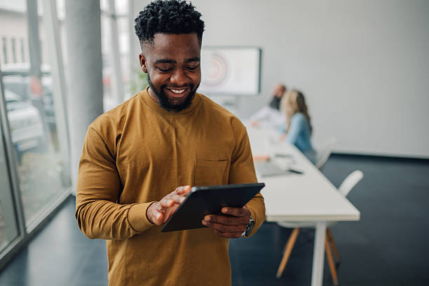 istock Young businessman using digital tablet in modern office with colleagues working in background 2212976270