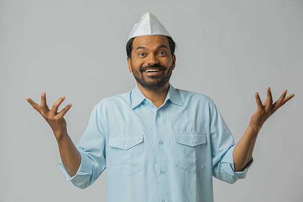 Portrait of cheerful mid adult driver wearing topi pointing with two hands while standing against white background