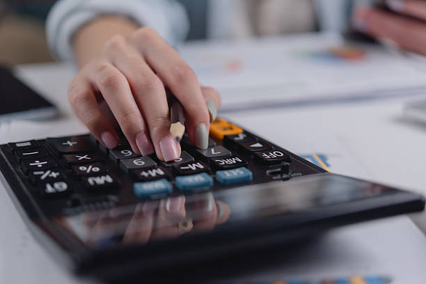 istock Female hand pressing calculator keys with documents. Great for financial planning, accounting, tax return, budget strategy, and business paperwork visuals. 2212990440