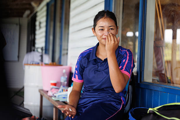 Happy young female cricket player applying sunscreen before play