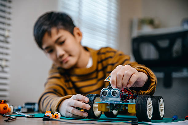 Child boy doing  robot homework project in house.