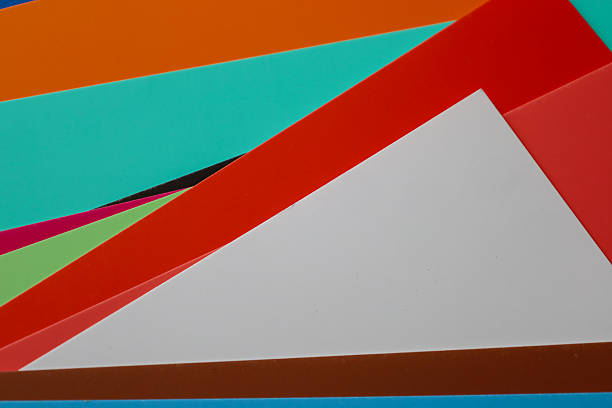 Brightly colored paper sheets of various hues overlap each other, creating an abstract composition of lines and planes in studio lighting in Sambir, Ukraine.
