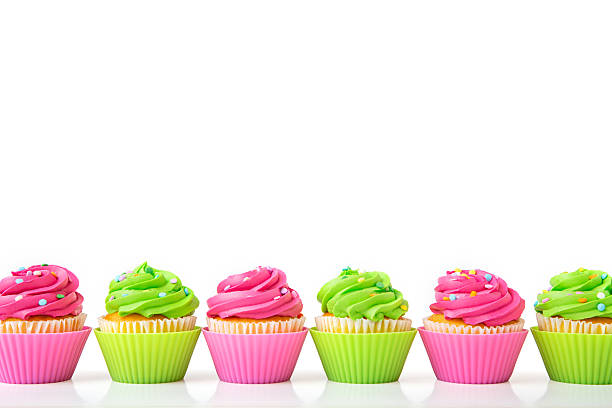 istock Colorful iced cupcakes arranged in row on white background 2212996982