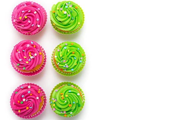 istock Colorful cupcakes with pink and green frosting arranged on white background 2212997043