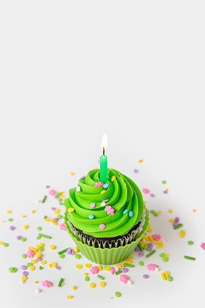 Colorful cupcake with green frosting and candle for special celebration