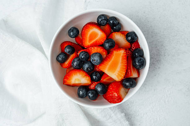 istock Fresh strawberries and blueberries in a bowl on a light surface 2212999011