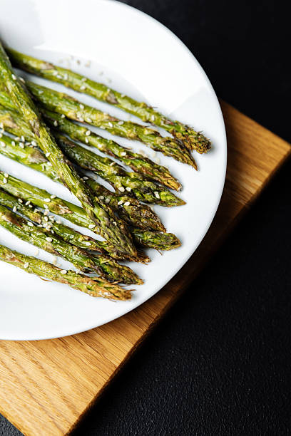 istock Grilled asparagus spears with sesame seeds on a wooden board 2212999033