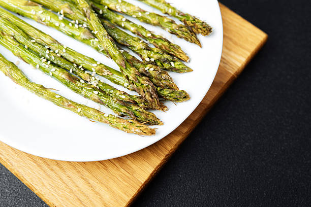 istock Grilled asparagus spears served on a white plate with sesame seeds 2212999037
