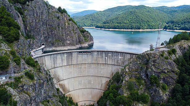istock Massive Concrete Dam Between Mountain Ranges Holding a Vast Reservoir Lake 2213000536