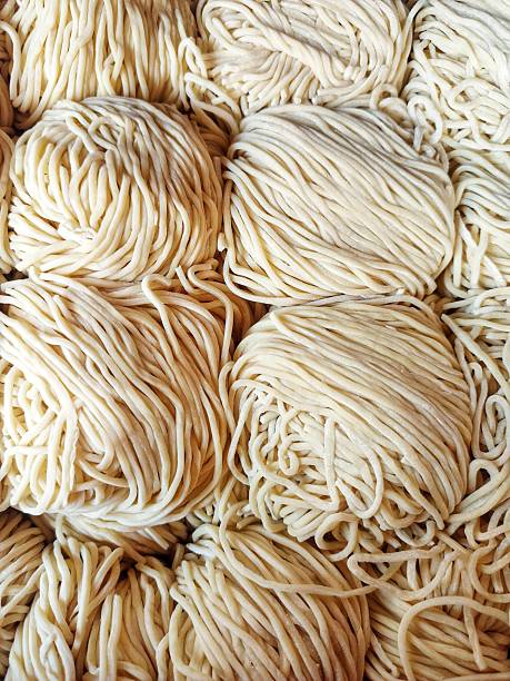 istock Freshly made Chinese egg noodles arranged in tight bundles, highlighting their smooth texture and classic golden color 2213002163